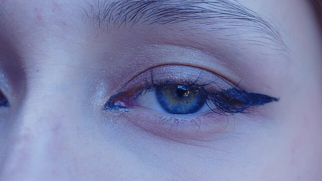 A beautiful girl with sensual light blue eyes stares intently at the camera in a close-up shot.
