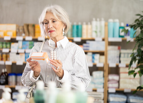 Mature woman in summer clothes buys paracetamol medicine at a pharmacy