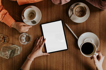 Obraz premium Overhead view of friends enjoying coffee around tablet