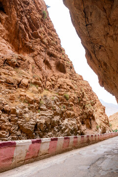 Road winding through the dramatic Dades Gorge a narrow canyon with towering red limestone rock formations showcasing the rugged beauty of Moroccos Atlas Mountains