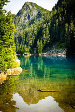 Clear turquoise mountain lake reflecting evergreen forest and a rocky peak
