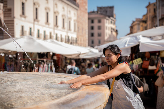 Woman reaching into a fountain on a hot day in Verona, Italy