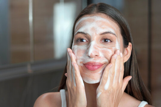 Mousse facial cleanser for oily skin. Skincare woman washing face foaming facewash soap scrub on skin.