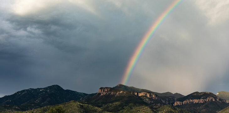 Bright rainbow rising from a peak in the Huachuca Mountains