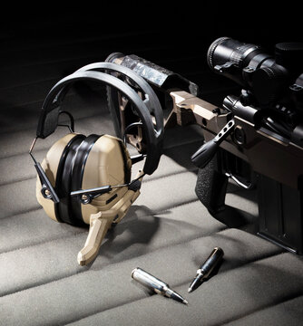 Ammo and hearing protection with two way radio inside next to a rifle