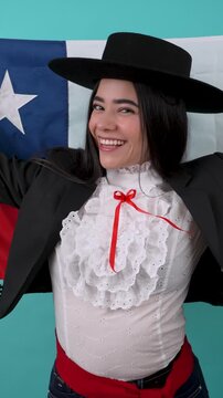 Beautiful chilean woman wearing a typical cueca dress dancing with the flag of chile