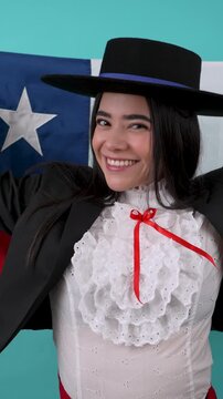 Beautiful chilean woman wearing a typical cueca dress dancing with the flag of chile