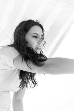 Black and white portrait of a woman beneath a beach parasol