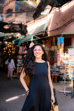 Young Latin woman smiling and carrying a shopping bag while exploring a vibrant traditional marketplace in Marrakech experiencing the local culture and enjoying her travel