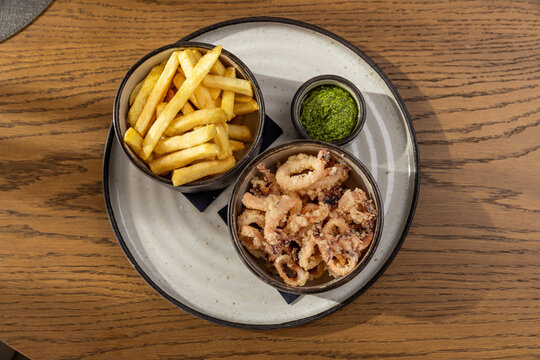Crispy fried calamari with french fries and pesto dip top view