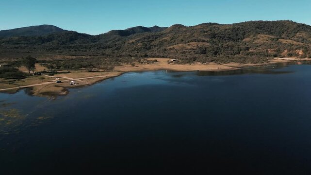 Drone flight over a still reservoir framed by rolling hills