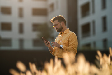 Young man using smartphone outdoor during golden hour