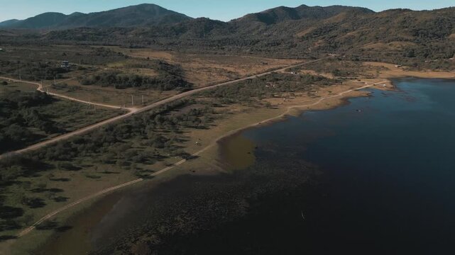 Aerial drift over a winding reservoir shoreline flanked by dusty hills