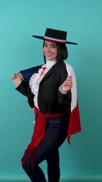 Young Chilean woman in traditional huasa dress holding the national flag celebrating national holidays