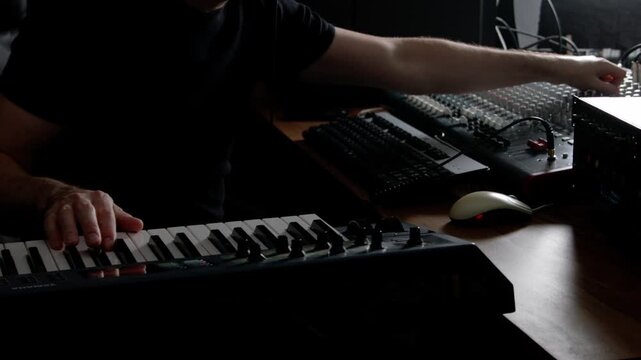 Live audio mix of musical performance on DAW with analogue mixer, synth, and outboad rack gear effects, compressors, reverb and delay, and other audio processors. Dark, backlit lighting