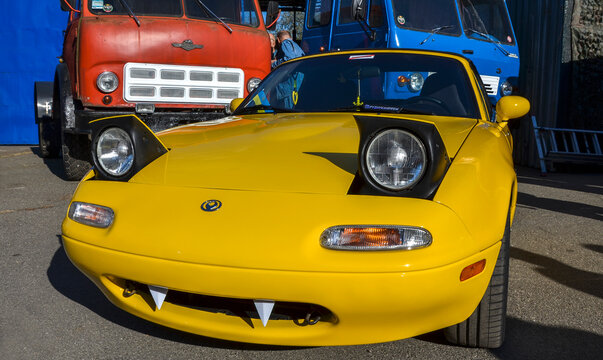 Vibrant yellow Mazda MX-5 Miata NA highlights its iconic pop-up headlights and custom white wheels, a beloved JDM roadster celebrated for pure driving culture