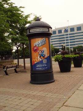 Gatineau, Quebec, Canada &ndash; July 04, 2026: An outdoor view showing a cylindrical public advertising pillar displaying a promotional poster with the text "Profite de l'&eacute;t&eacute;!" on Bd de la Gappe.