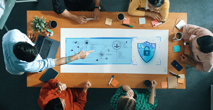 A diverse group of professionals collaborates in a modern office, focused on a large strategic planning document about security. Engaging discussion fosters innovation. Trope