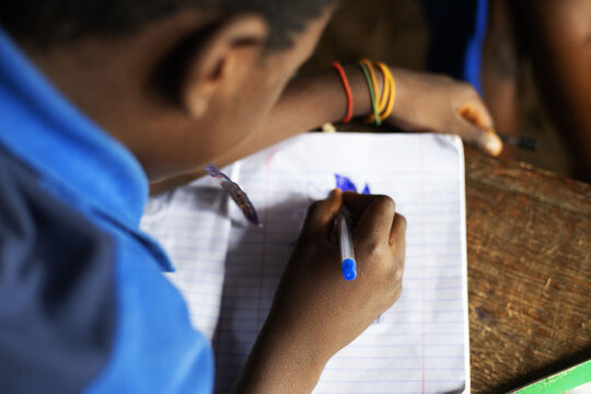 A young African boy sketching on a paper