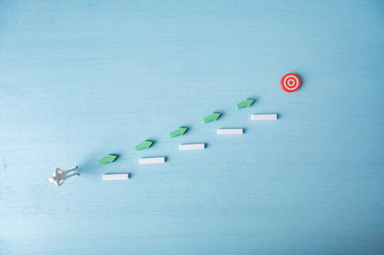 Path to success and goal achievement with person following arrows and steps toward target