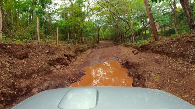 Off-road car driving through muddy puddle in jungle
