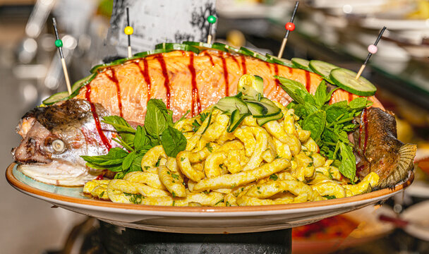 Whole cooked salmon beautifully dressed and garnished on a luxury hotel open buffet platter.