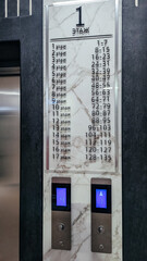 Elevator directory panel with marble surround, listing floors 1-17 in Russian  two blue-lit up/down call buttons. © Екатерина Говорина