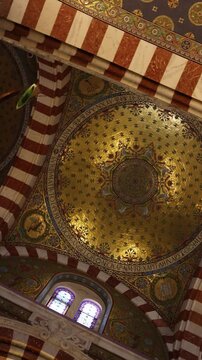 Ornate altar and richly decorated apse inside Notre-Dame de la Garde Basilica in Marseille, France. Golden mosaics, colorful religious artwork and a statue of the Virgin Mary highlight the sanctuary