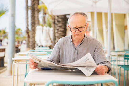 News in the newspaper; a man wearing glasses reads a column