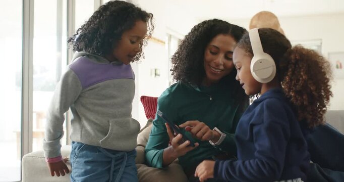 African American mom sharing phone music with daughters at home girls wearing headset and reacting