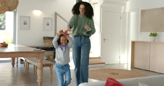 African American mother lifting child's hands, twirling, jumping at home, smartwatch cueing play