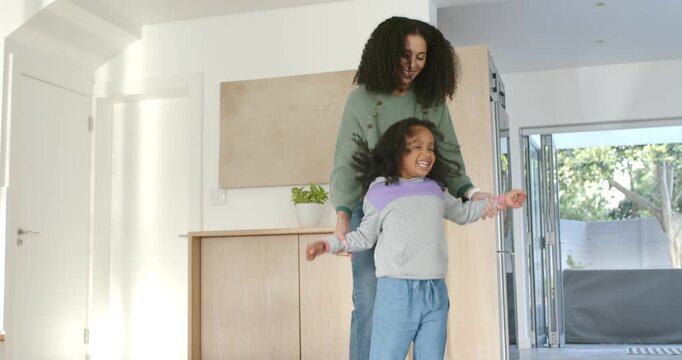 African American mother and child playing, guiding child spinning and hugging near sliding doors