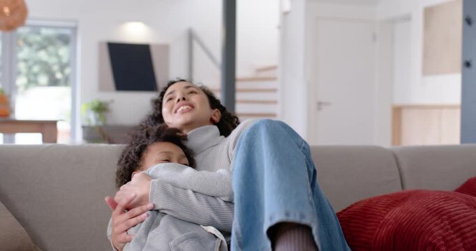African American woman holding and hugging child, child pressing in and seeking comfort on couch