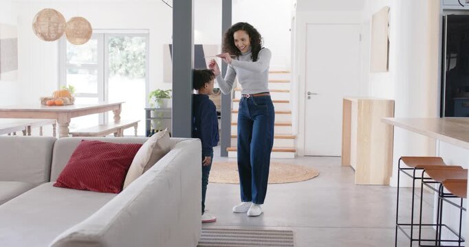 African American mother and child, mother marking height with pen on column at home, checking phone