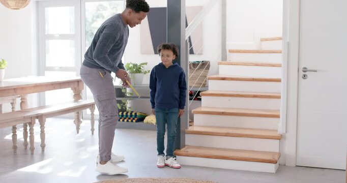 African American man and youth in foyer, arriving man measuring her height with tape for growth