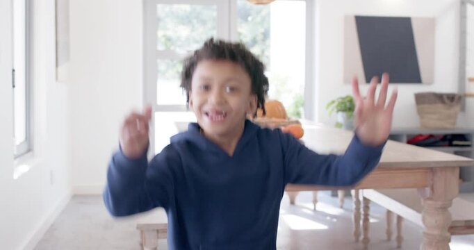 African American child in hoodie entering dining area running to cam smiling showing missing tooth