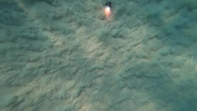 Slow motion of power waves creating sand motion patterns  with an underwater light at  the bottom 