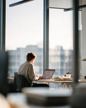 focused professional working alone in a quiet contemporary office with minimal desk setup, notebook, laptop and neutral stationery, realistic commercial lifestyle photography