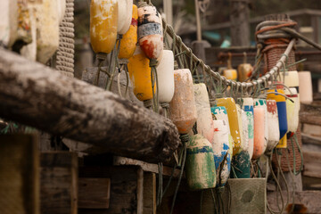 Foggy autumn view of vintage buoys hand on a wooden dock on the beach of Pacifica, California, USA. © Matt Gush