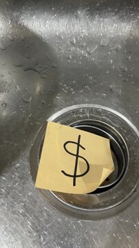 Dollar sign note on kitchen sink drain water cost concept