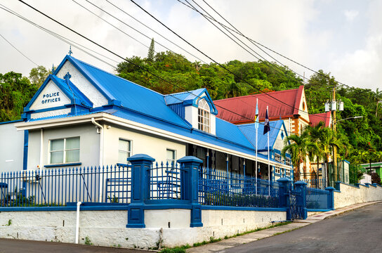 Colonial police station building with a blue metal roof and iron fence along a street in Castries, Saint Lucia.