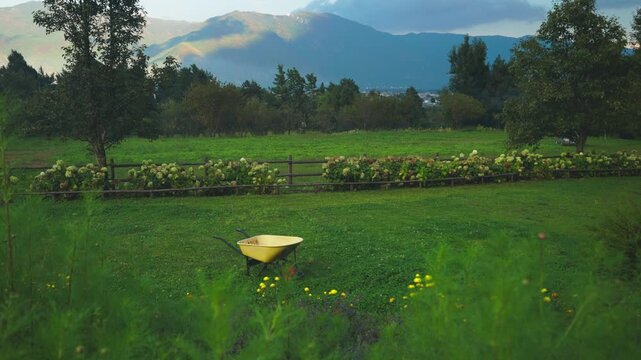 Green Lawn with Yellow Garden Cart and Mountainous Garden View