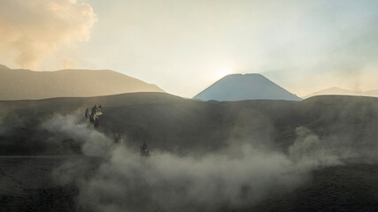 Tenggerese horse riders crossing the volcanic landscape around Mount Bromo in East Java, Indonesia, surrounded by drifting volcanic sand and dust. © huong