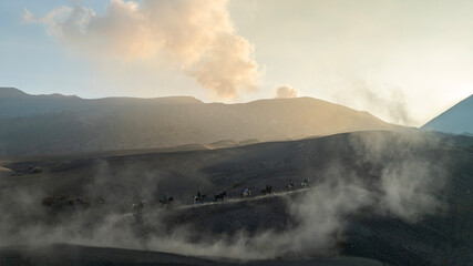 Tenggerese horse riders crossing the volcanic landscape around Mount Bromo in East Java, Indonesia, surrounded by drifting volcanic sand and dust. © huong