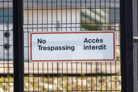 No Trespassing Access Interdit Sign on Black Chain-Link Fence