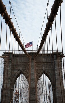 Symmetrical vertical view of Brooklyn Bridge stone tower with American flag