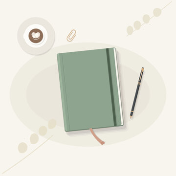 Green notebook with coffee and pen on desk