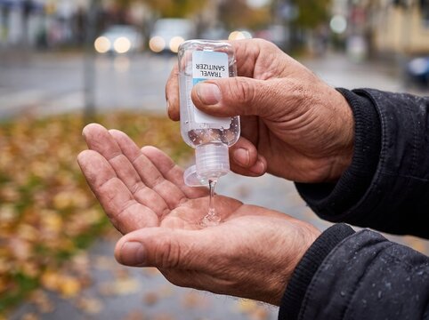 Close-up of hands using hand sanitizer outdoors during daytime.