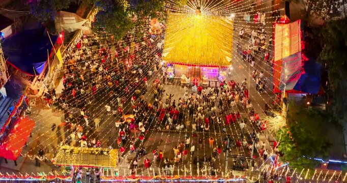 Kathmandu, Nepal, high-angle drone shot over the vibrant Maitidevi Temple premises, decorated with golden string lights and surrounded by crowds during Tihar.