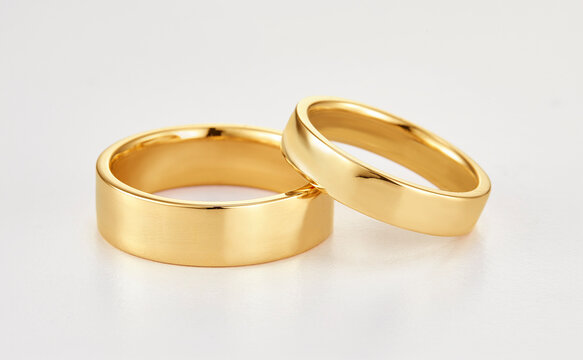 Pair of polished gold wedding bands rings isolated on white background close up